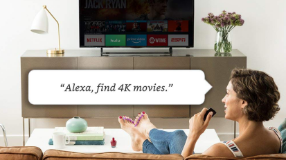 Person sitting on couch in front of tv holding fire stick with speech bubble saying "Alexa, find 4k movies"