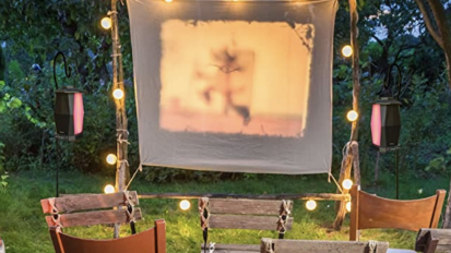 bluetooth speakers as part of an outdoor movie setup with string lights and a projector