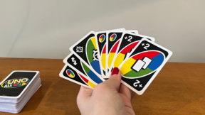 Manicured hand holding UNO cards next to an UNO card stack